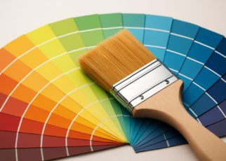 A paintbrush resting on a fanned-out array of color swatches in vibrant shades.